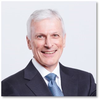 Un hombre con traje y corbata sonriendoDescripción generada automáticamente